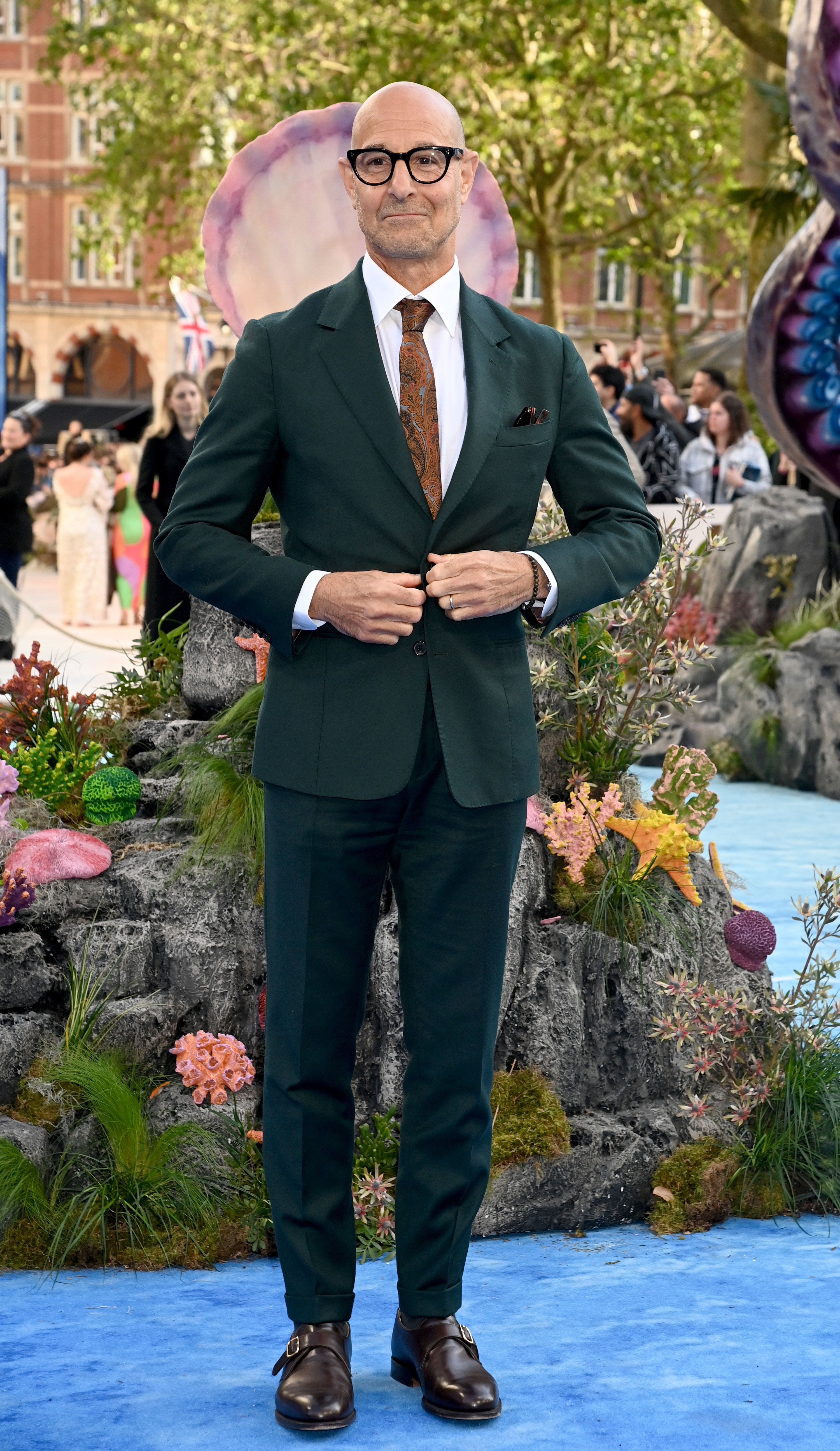 stanley tucci poses on a red carpet