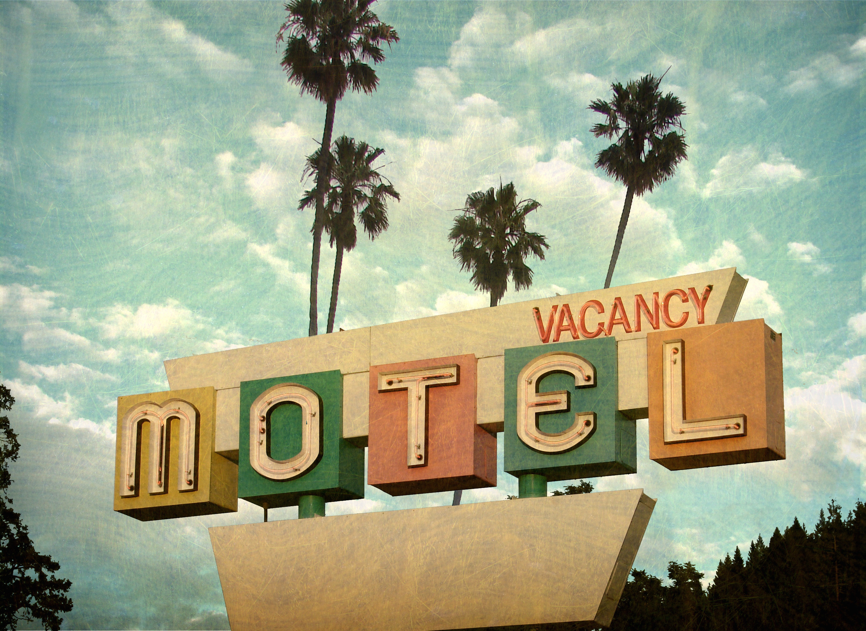 An aged and worn neon motel sign with palm trees