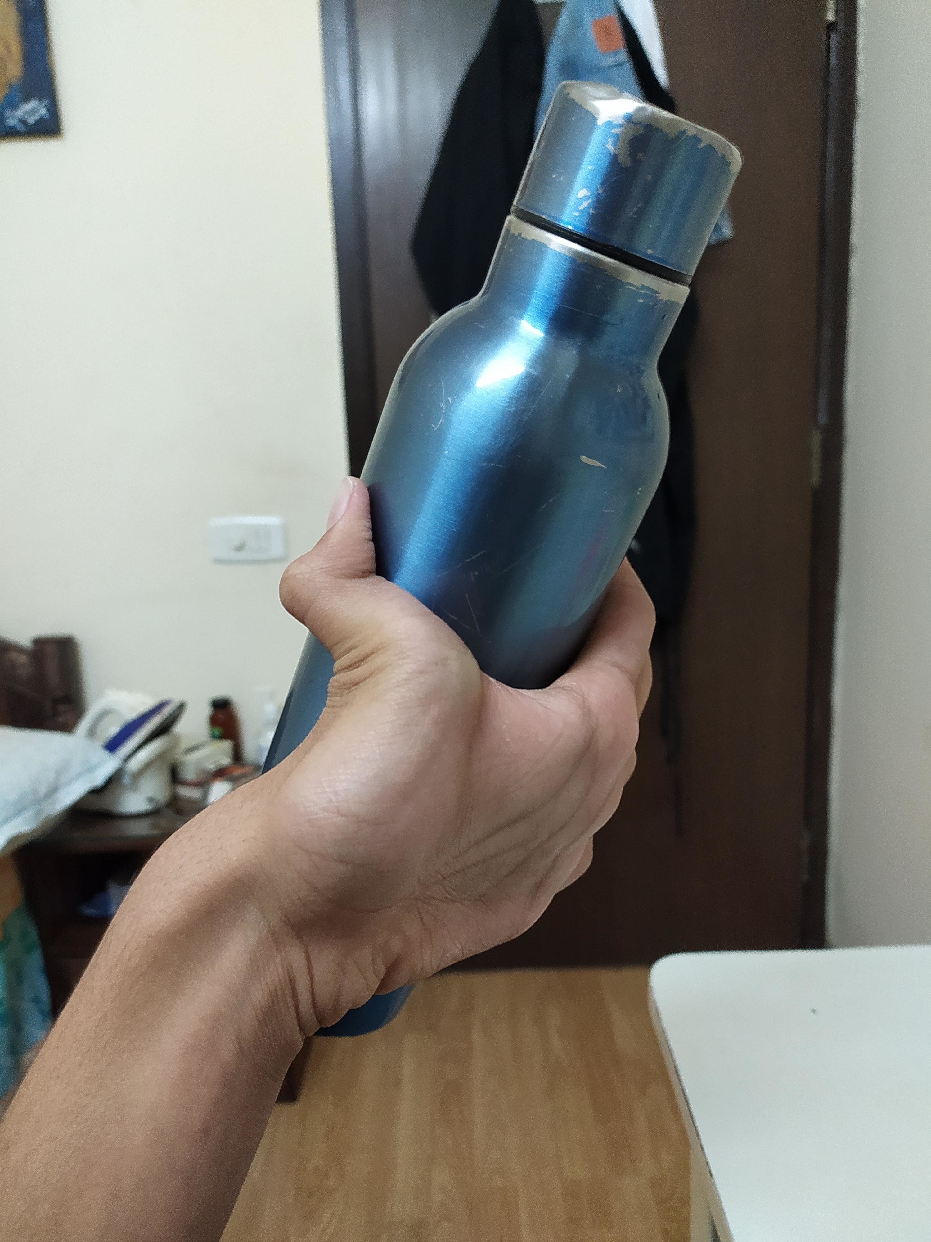 a person holding a water bottle with the backside of their hand, their fingers bending backwards