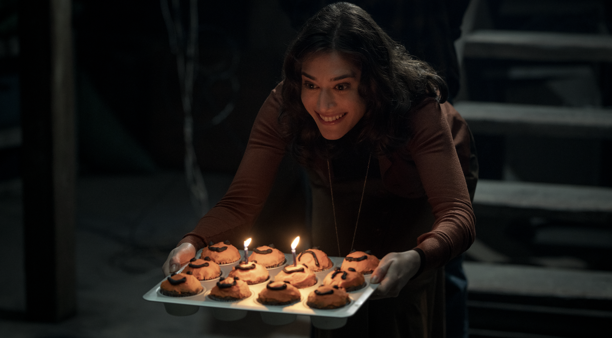 A woman holds a tray of cupcakes