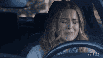A woman crying at the wheel in her car