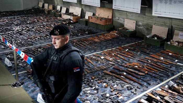 A Serbian police officer stands in front of weapons confiscated in the latest government disarmament action at a police depot near Smederev