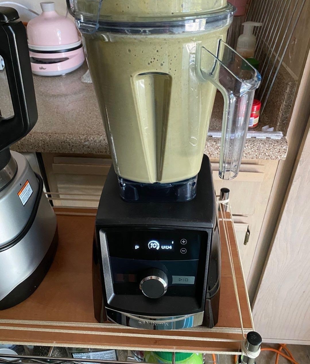 a reviewer photo of the blender with a green smoothie inside