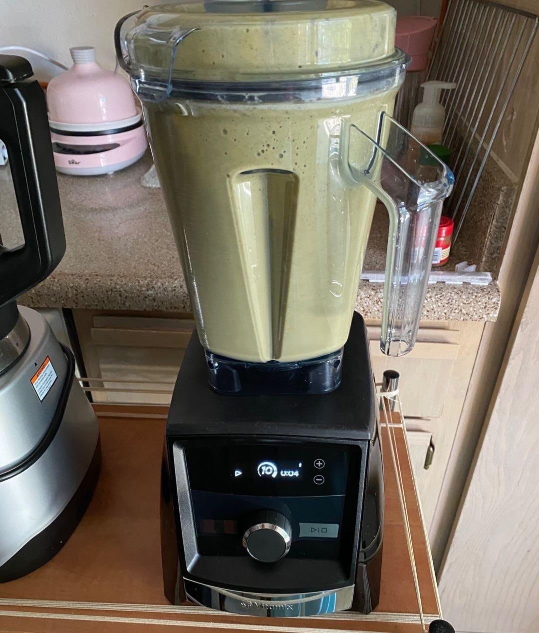 a reviewer photo of the blender with a green smoothie inside