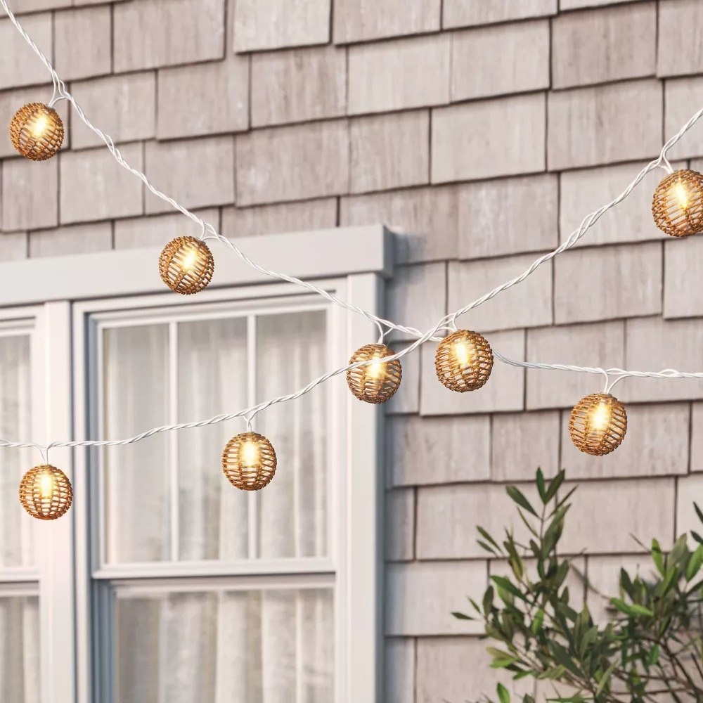 the string lights with rattan globe shades on each bulb hanging outside