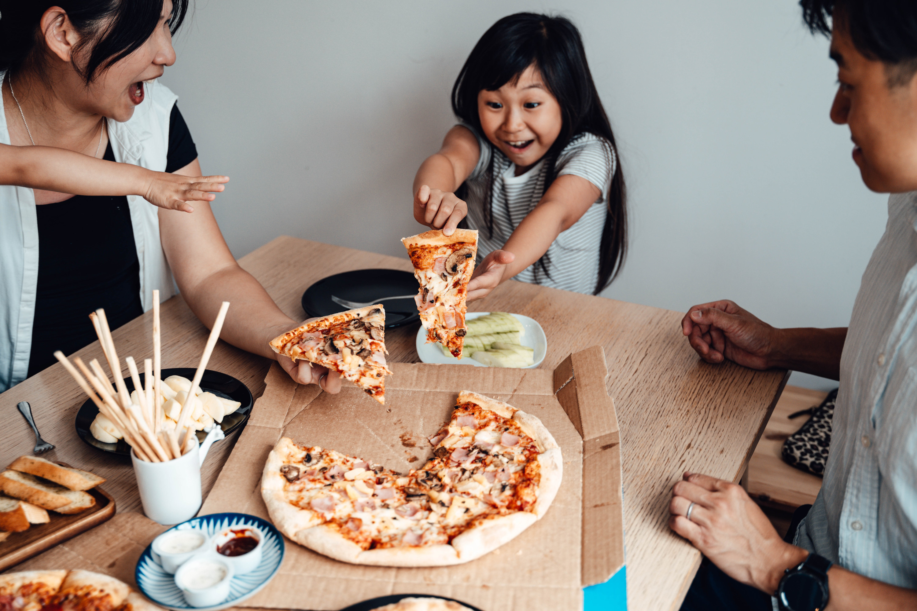 Family eating takeout pizza at home