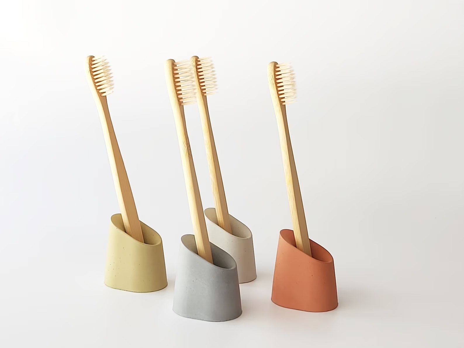 Four of the toothbrush holders in different colors, each with a toothbrush inside