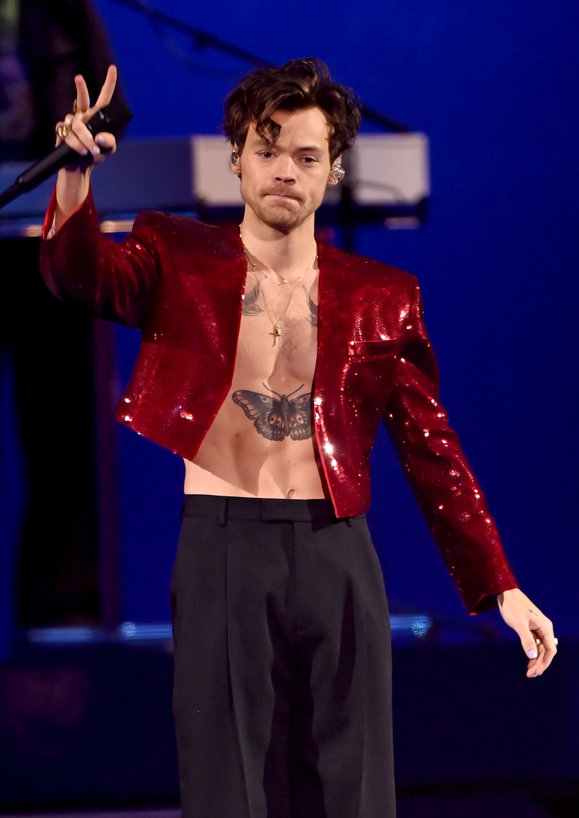 on stage with long-ish hair and shirtless under a blazer