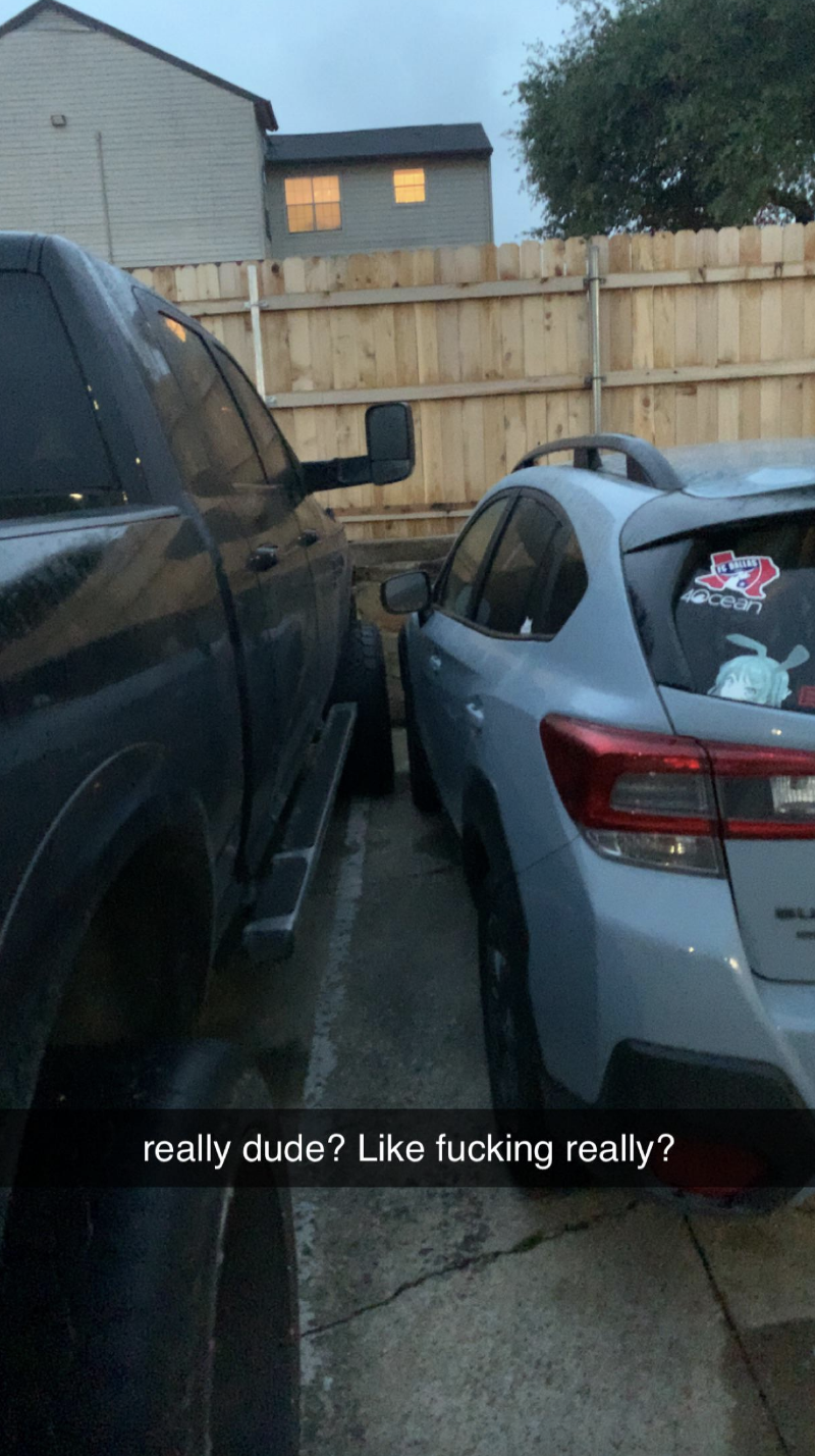 truck crossing over the line in a parking spot inches away from hitting another car