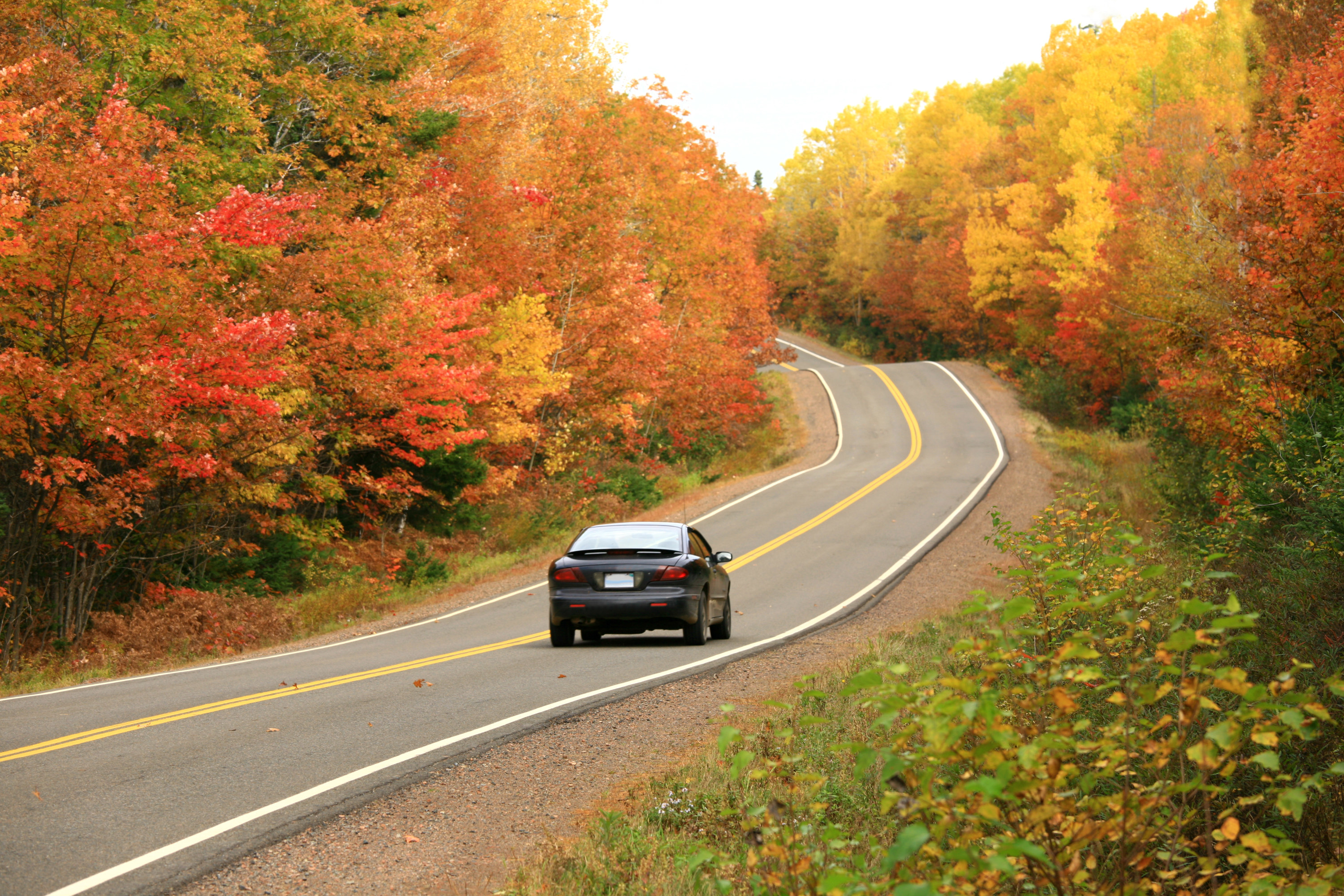 Car driving on a two-lane rural highway in autumn