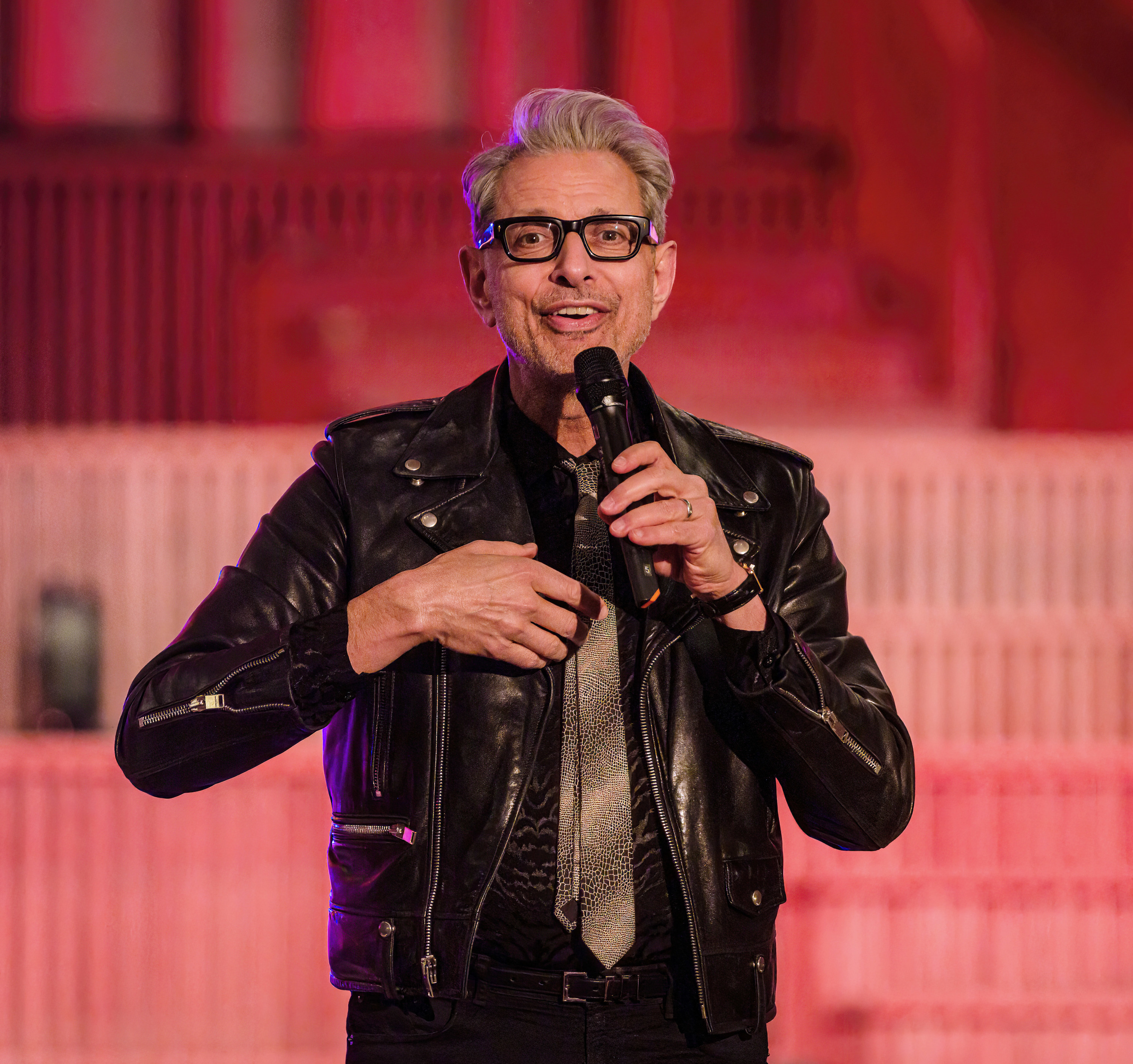 jeff goldblum on stage, holding a microphone