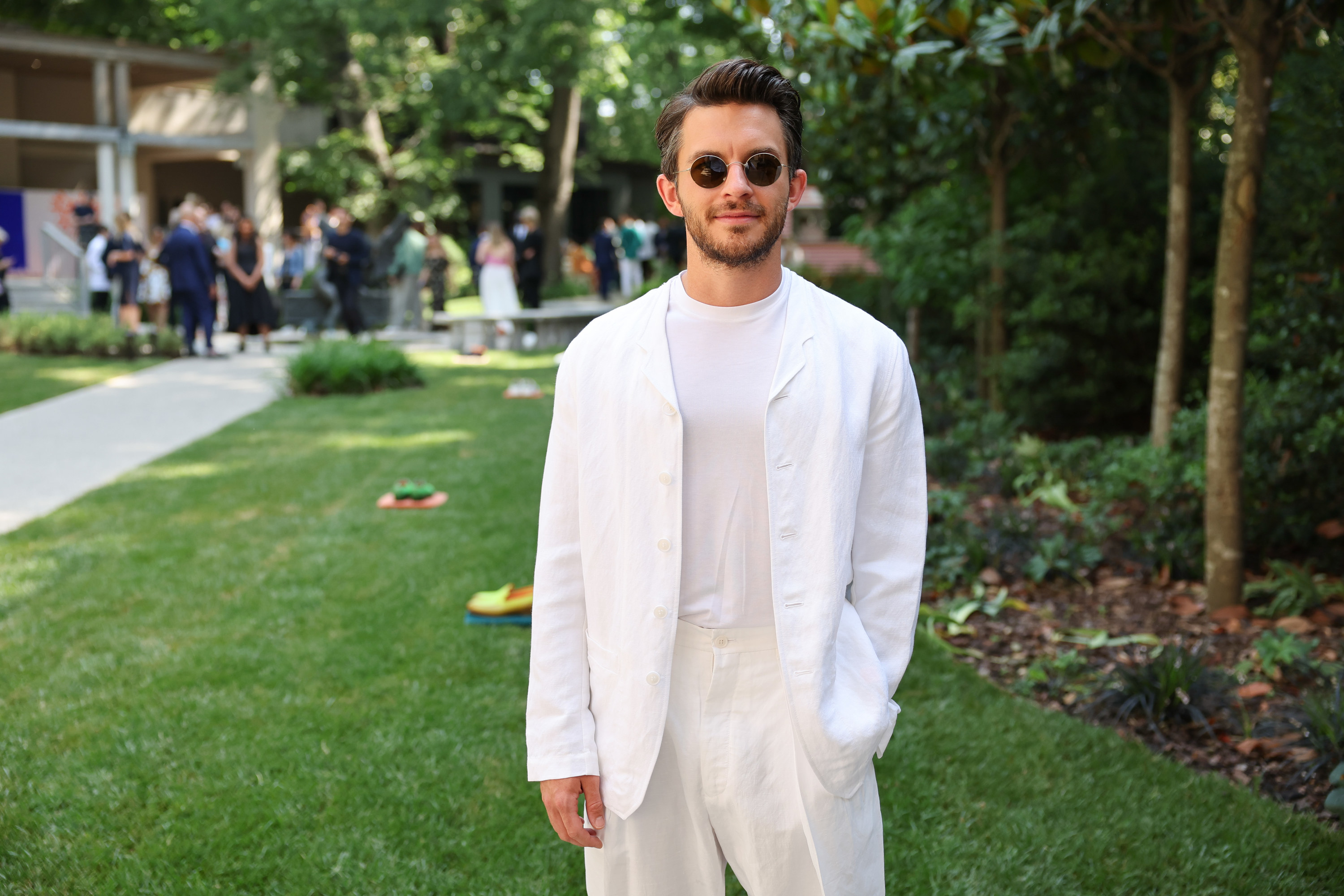 jonathan bailey poses for a photo while wearing a casual matching t-shirt, linen pants, and a light linen jacket