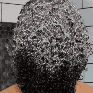 Someone running the turmeric hair detox mask through their curls