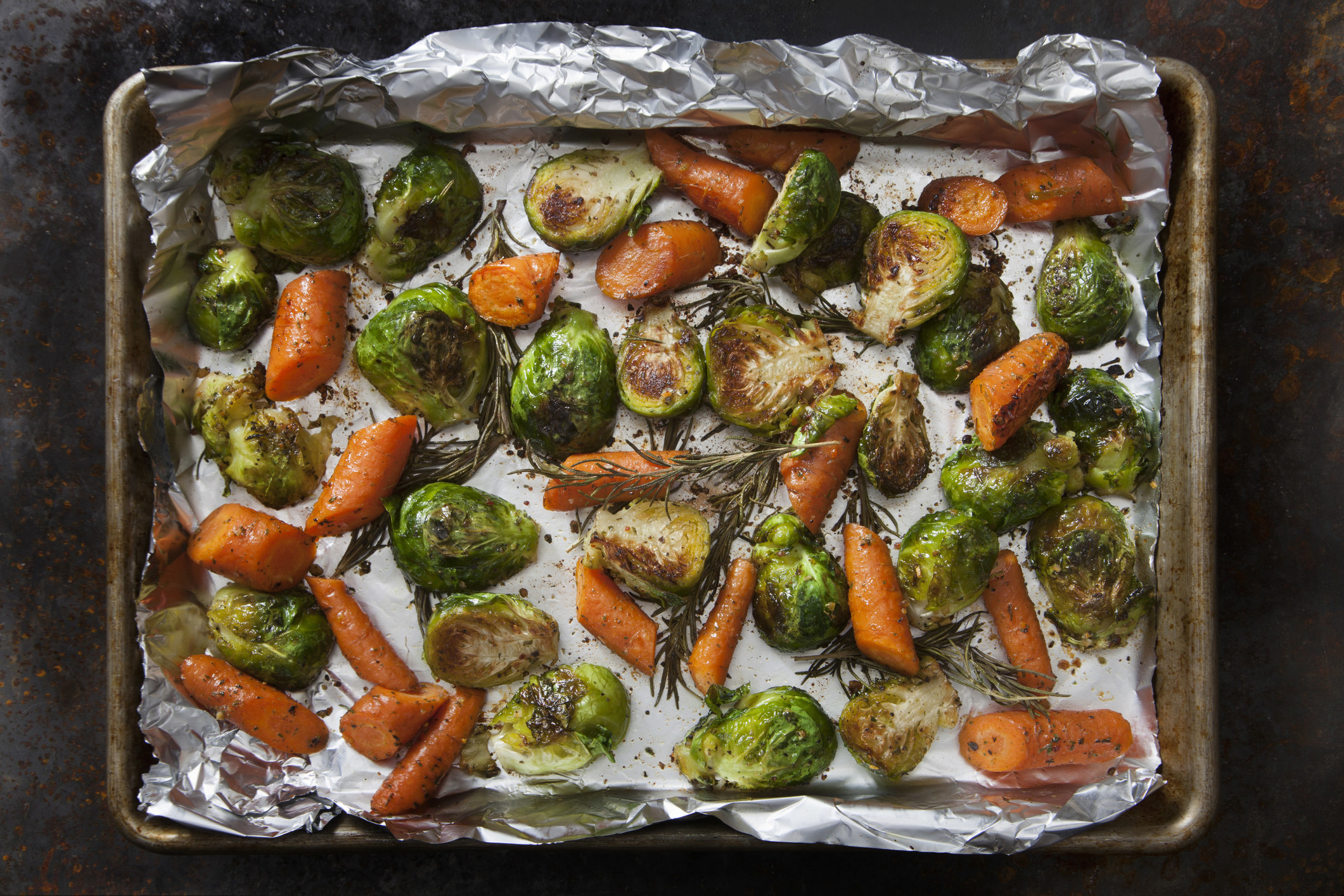 Roasted Brussels sprouts and carrots on a baking sheet.