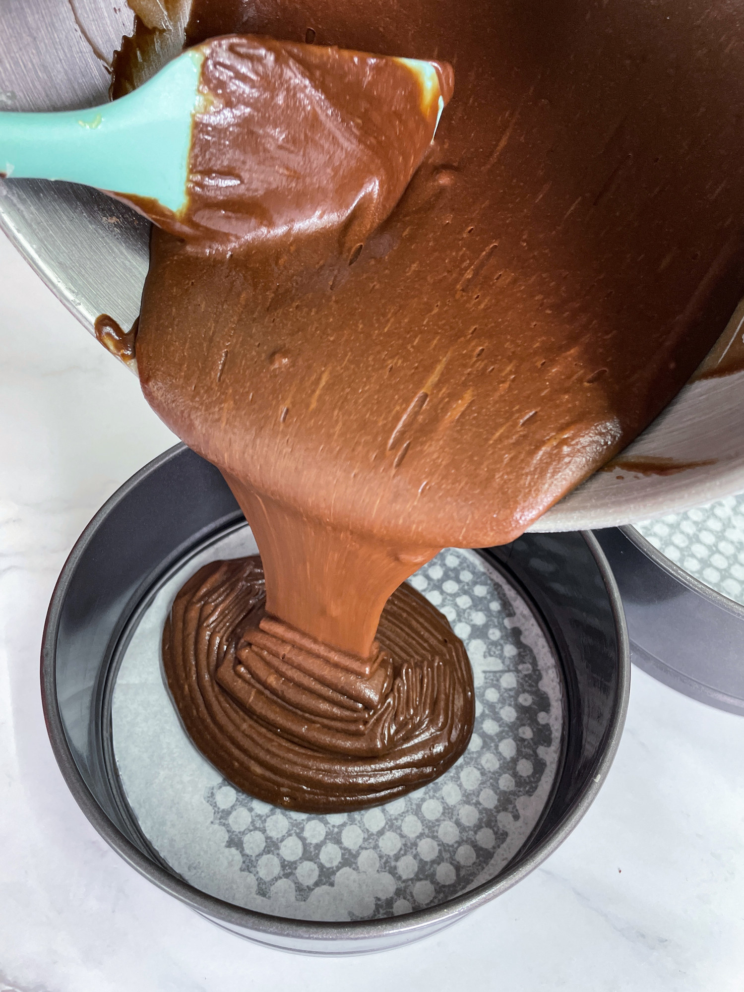 Pouring brownie batter into a baking pan.