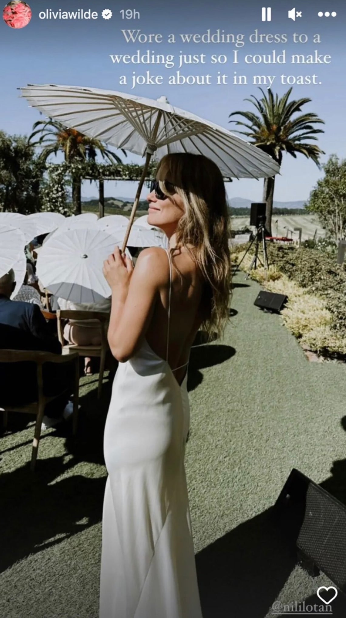 the instagram story of her in a silky wedding dress holding a sun umbrella