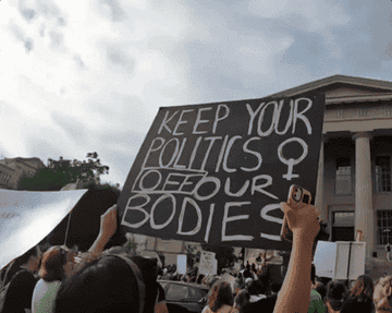 Protestor holding a sign that reads &quot;Keep your politics off our bodies&quot;