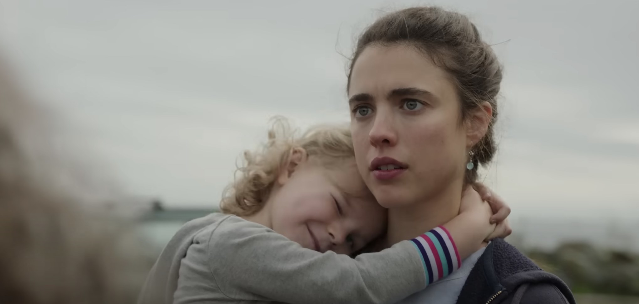 In the Netflix series, Maid, actor Margaret Qualley stares intently while the actor portraying her daughter clings tightly to her neck