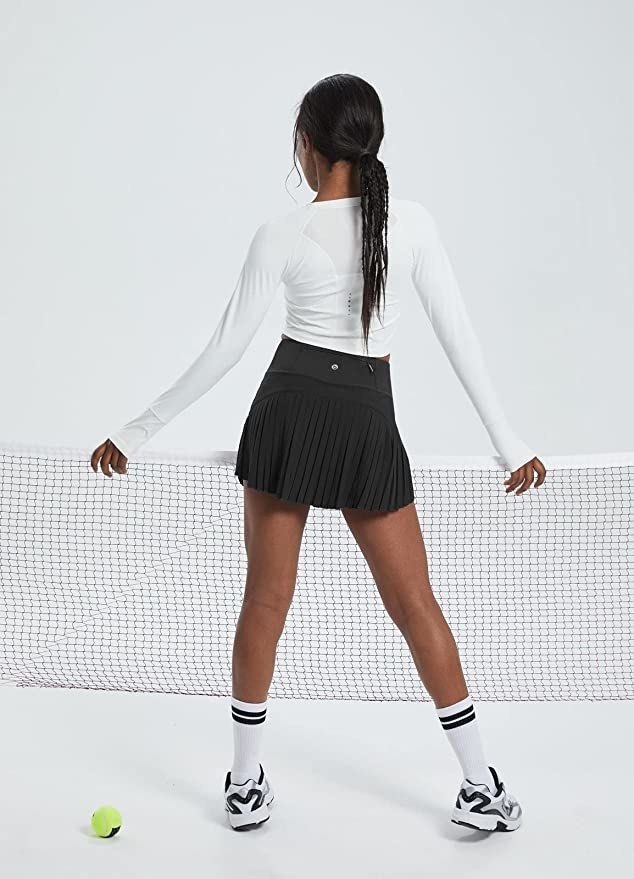 model from behind in black skirt in front of tennis net