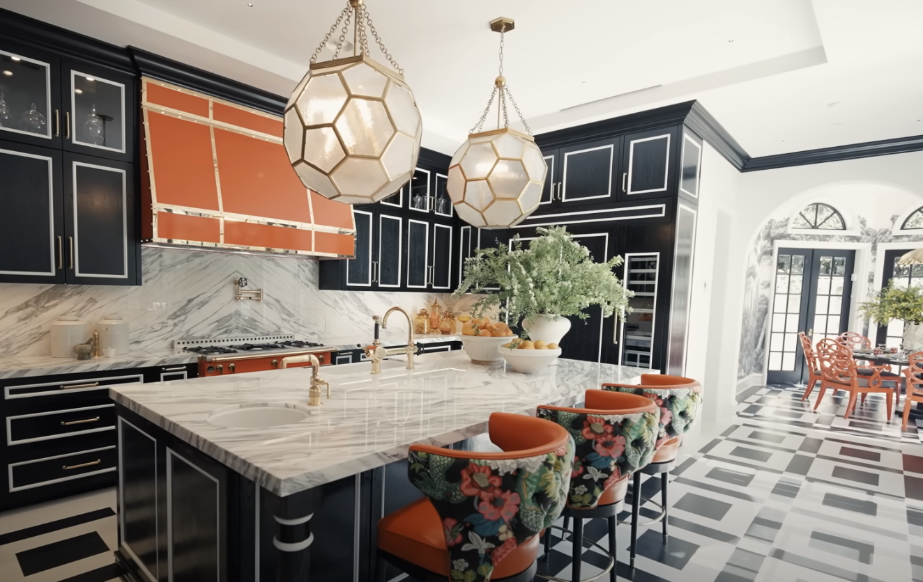 black and white accents all over the kitchen with an orange range and range hood