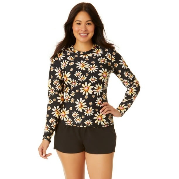 Model wearing black rash guard  with white floral design, paired with black shorts