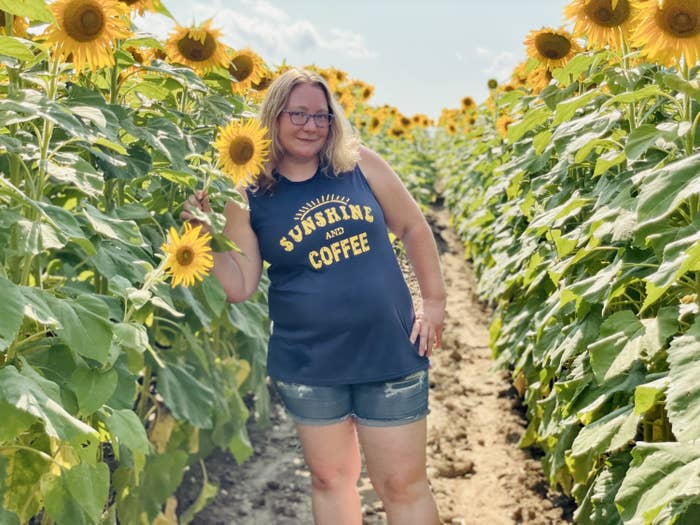 Reviewer in sunflower field wearing sunshine and coffee print tank with jean shorts