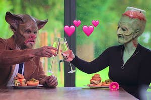 two people dressed in costumes clink glasses while on a date
