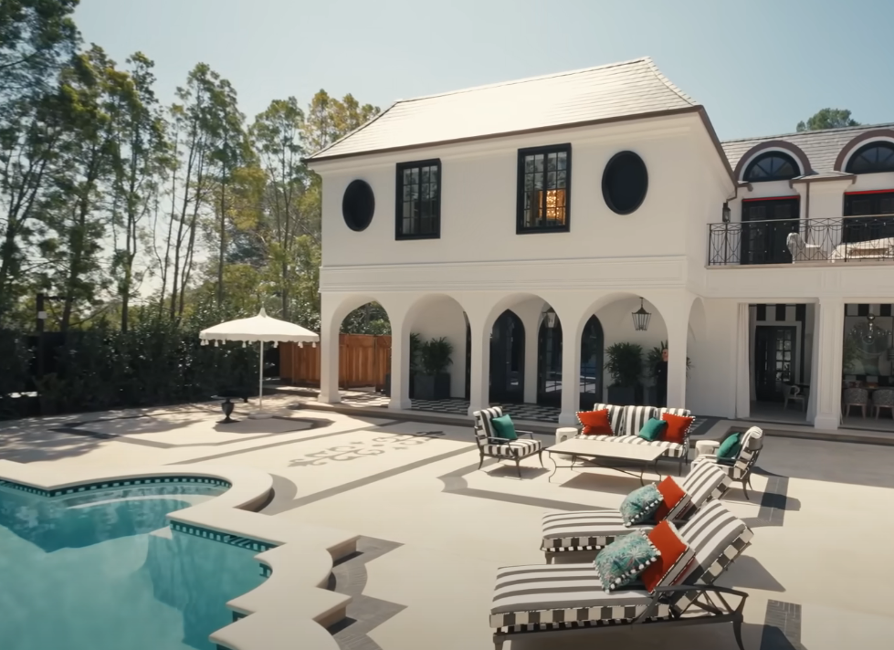white painted exterior of the home with a large pool and arched doorways
