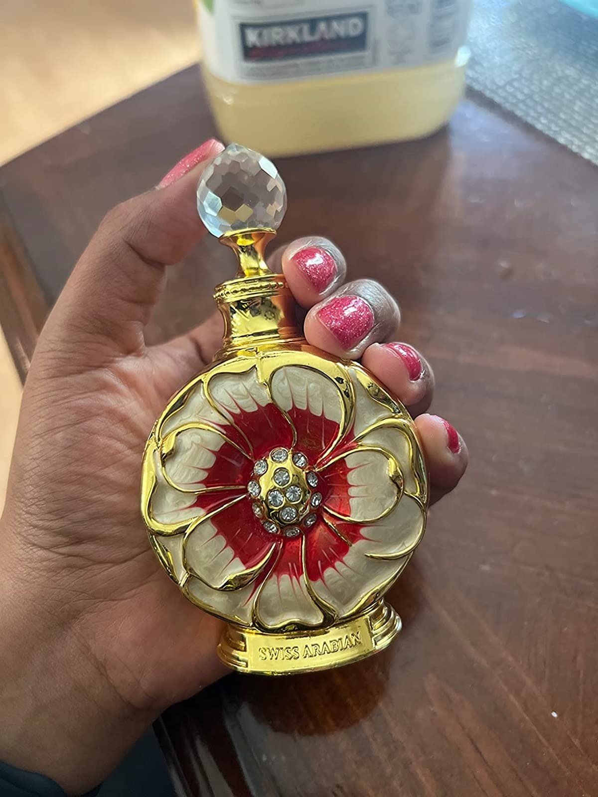 reviewer holding red floral-shaped perfume bottle
