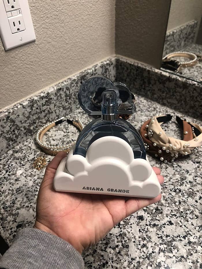 reviewer holding blue cloud-shaped Ariana Grande perfume bottle