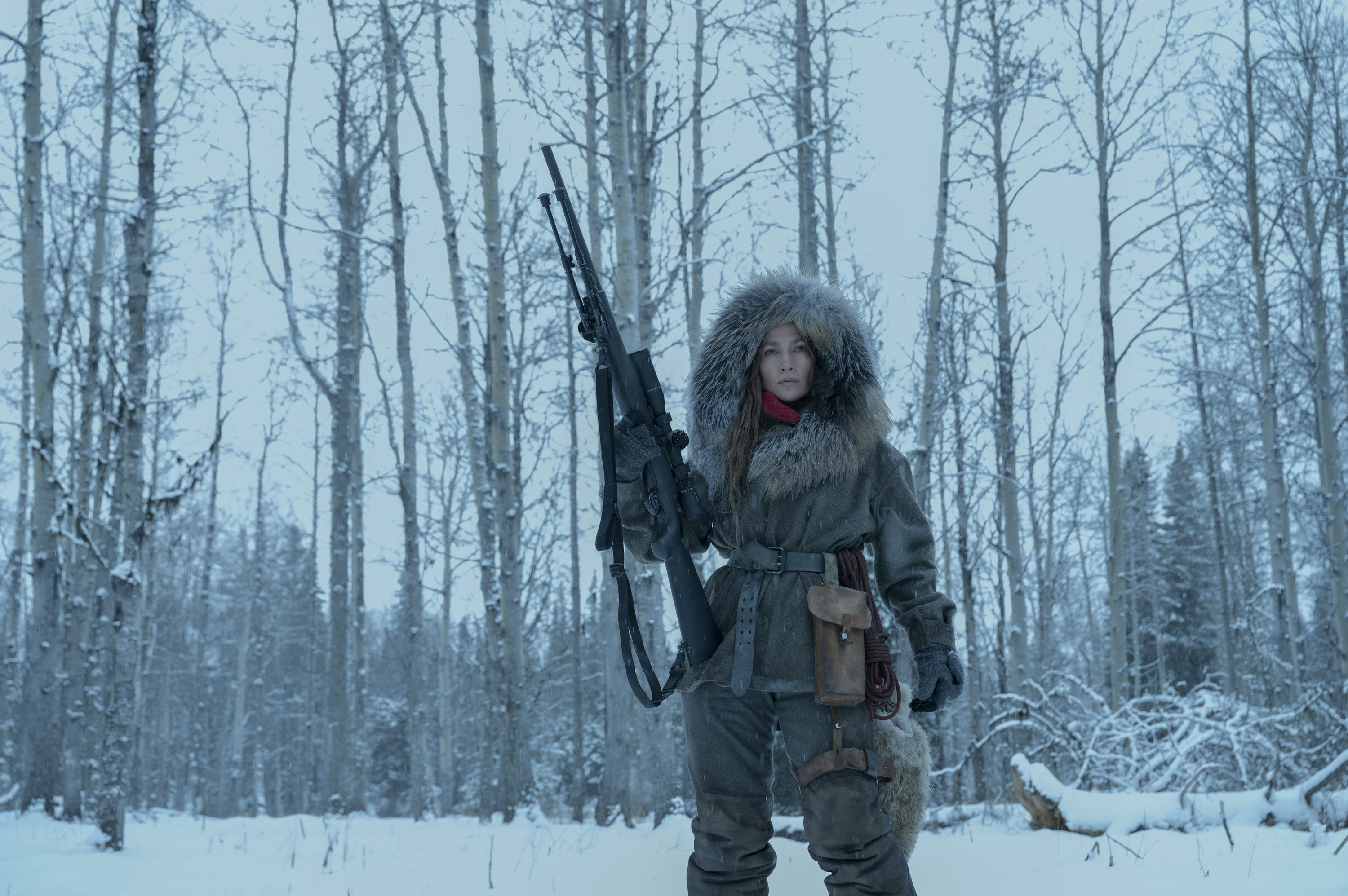 jennifer lopez holding a sniper rifle while standing in the cold wilderness in the mother