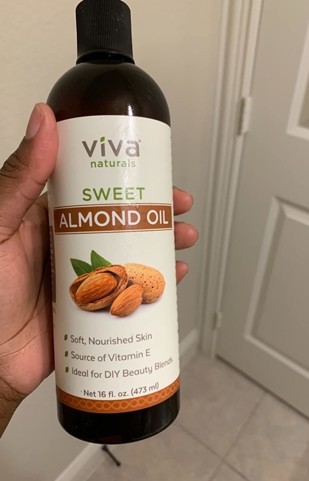 Reviewer holding their bottle of sweet almond oil