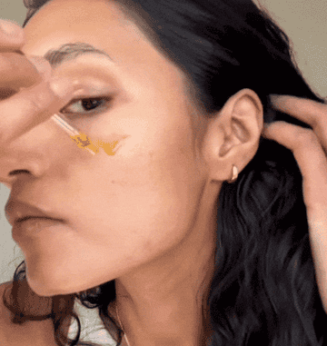 A woman applying serum to her face