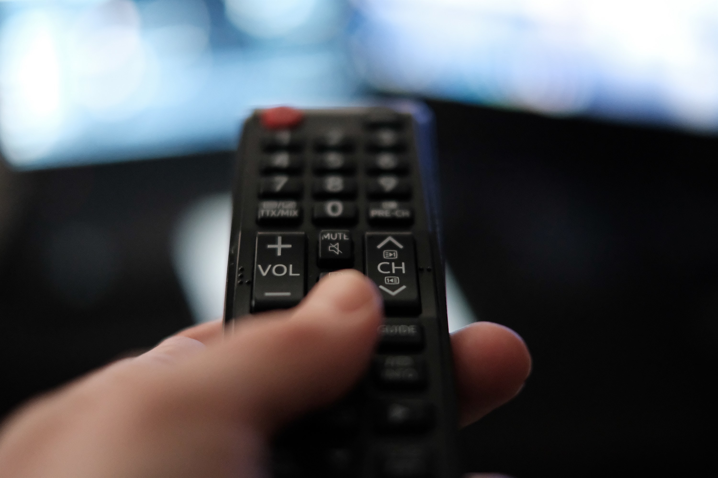 A person uses the remote to search through channels on the TV