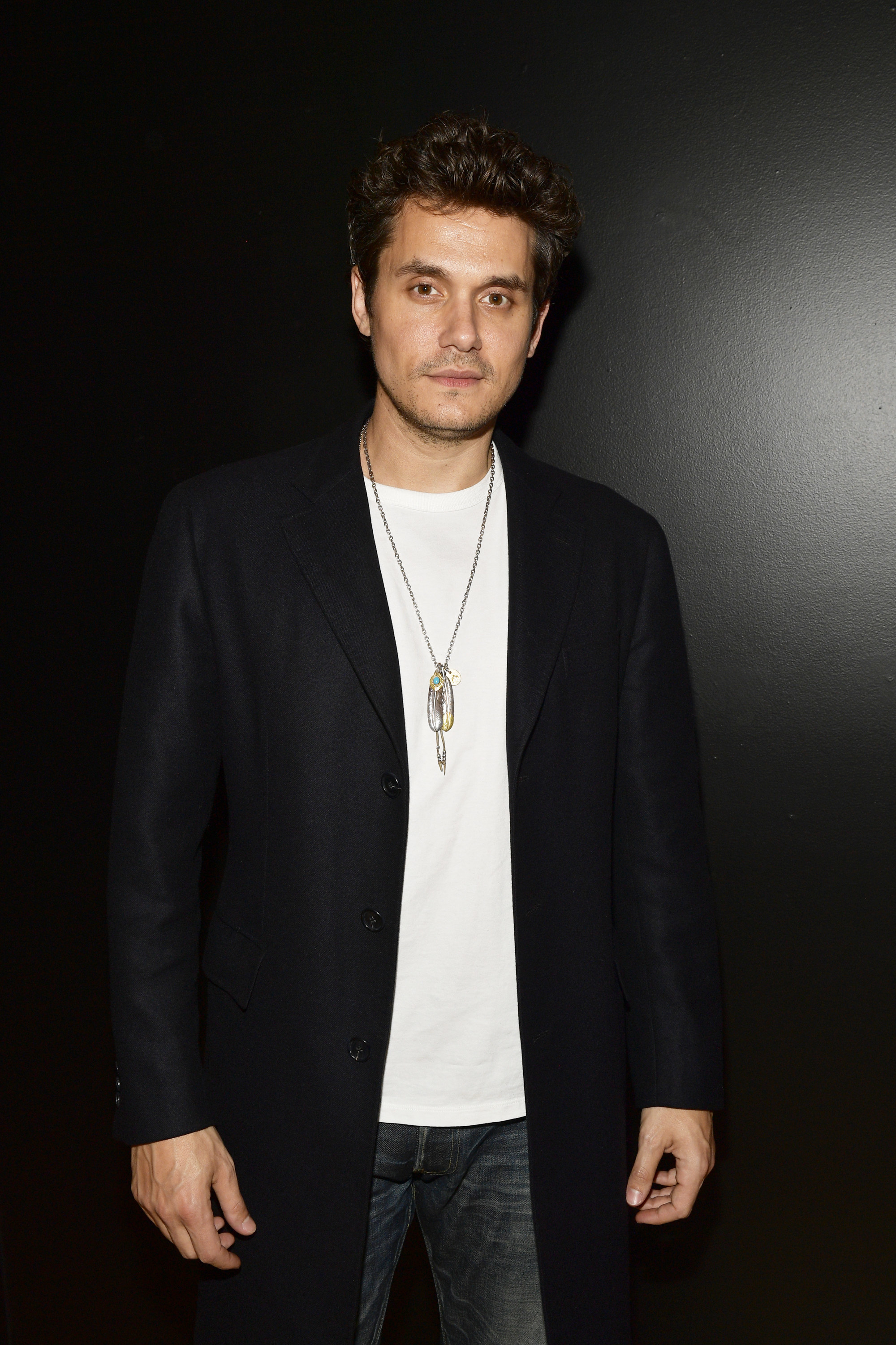 Mayer in jeans, a shirt, and a long suit jacket