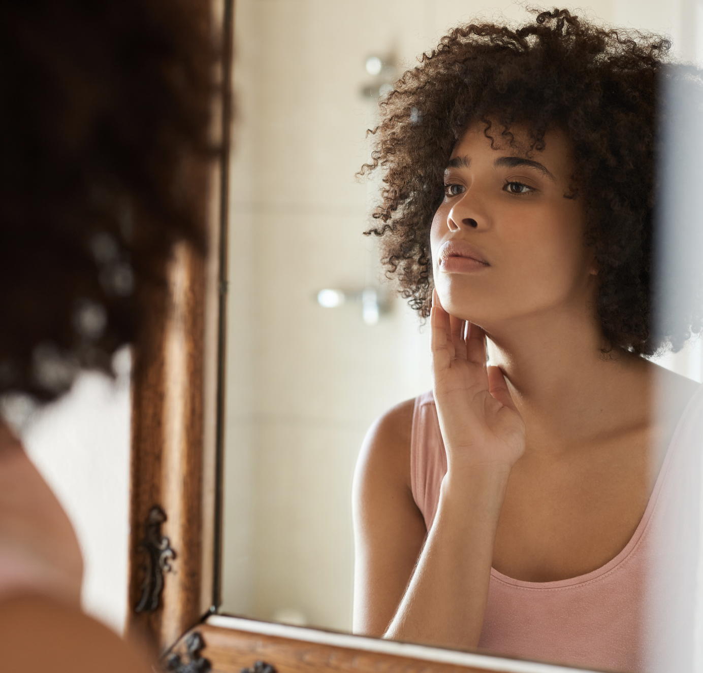 A woman staring at her reflection in a mirror in deep thought