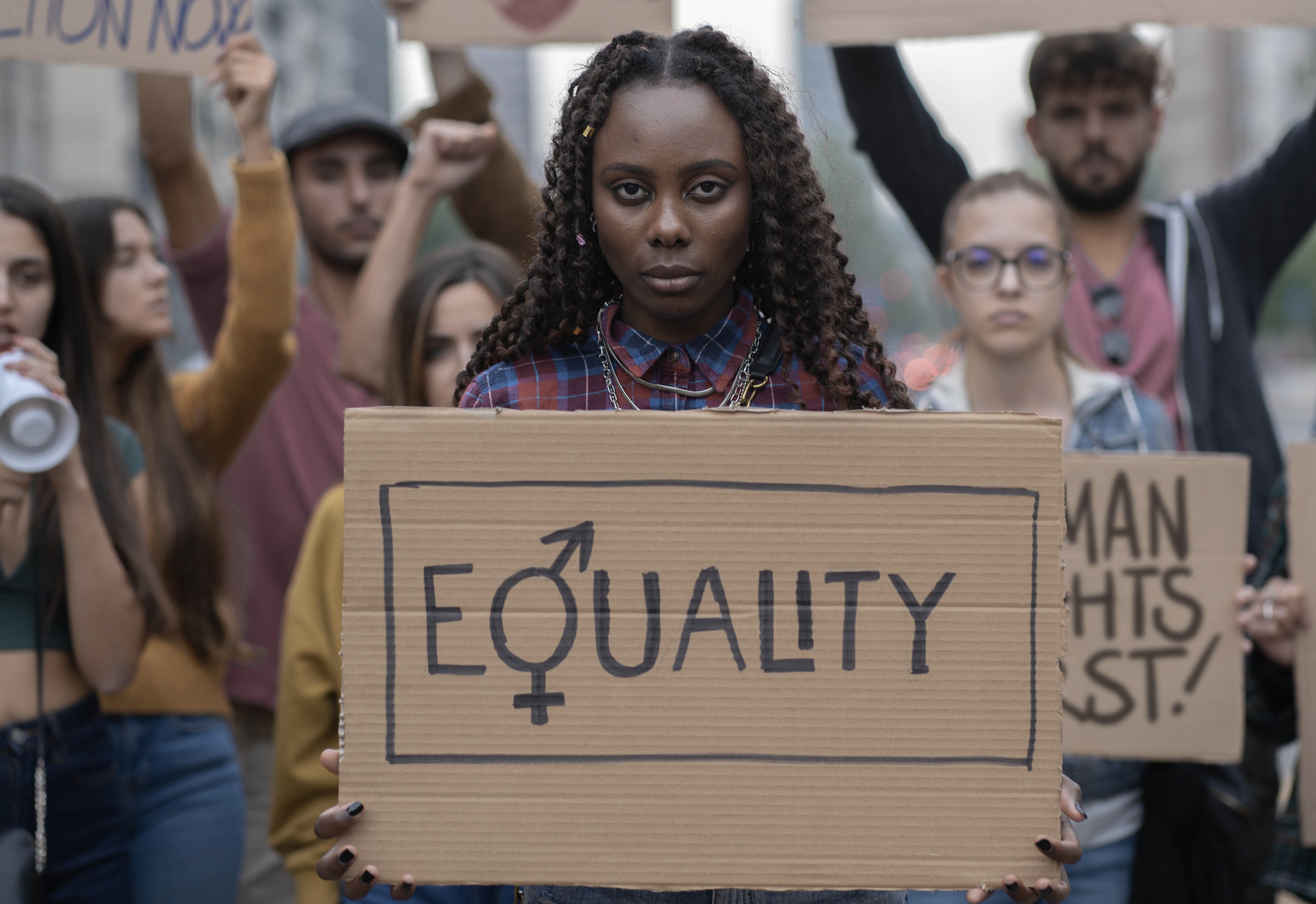 Woman holding up a sign that says &quot;Equality&quot; at a protest with other protestors behind her