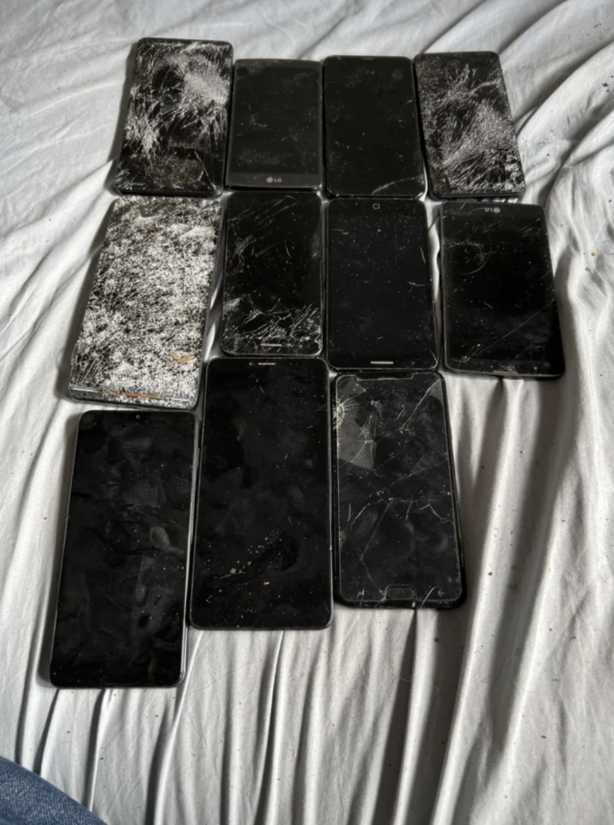 The 11 iPhones are lined up, all of them with badly cracked screens