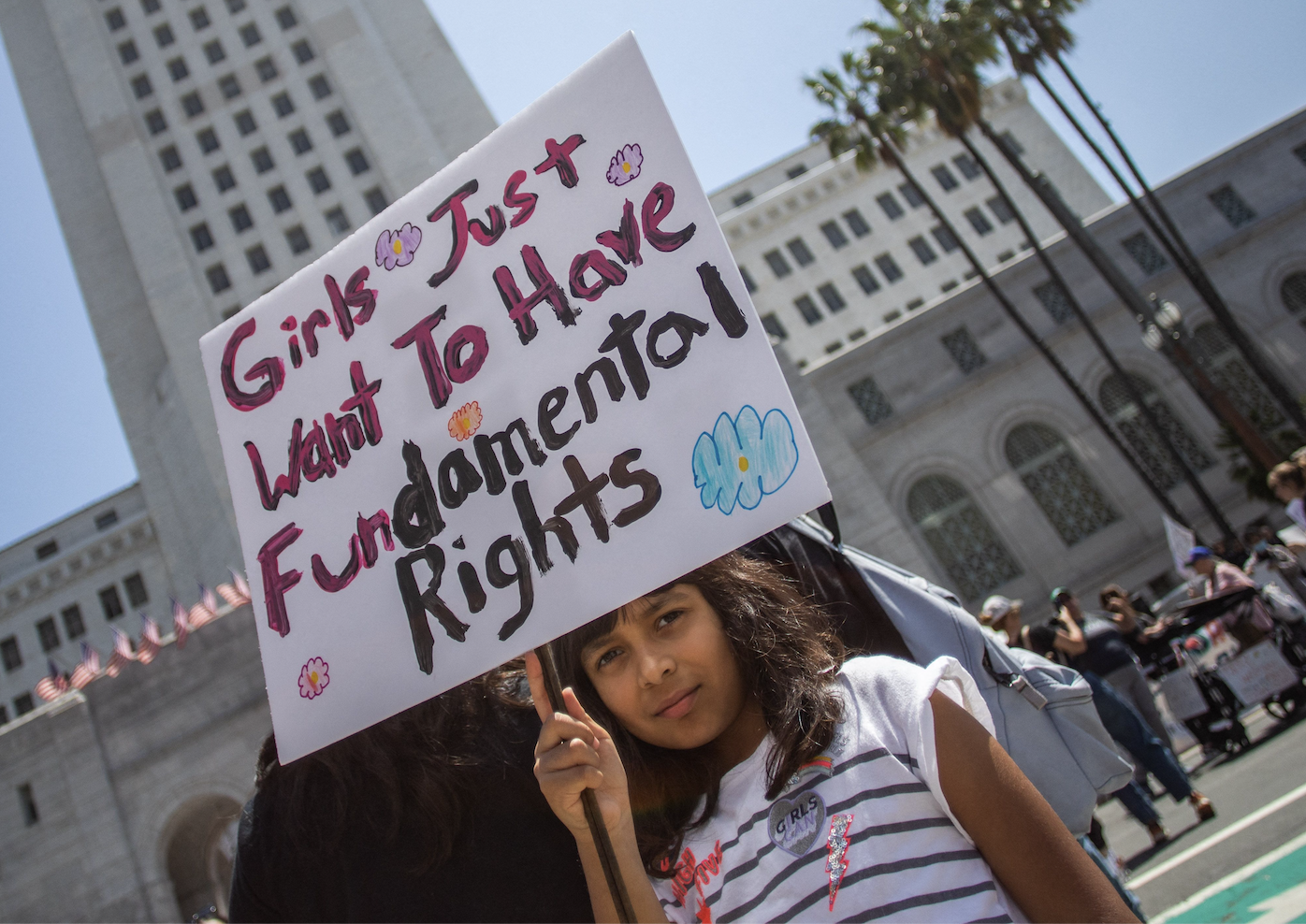 A young girl holding up a protest sign that says &quot;Girls just want to have fundamental rights.&quot;