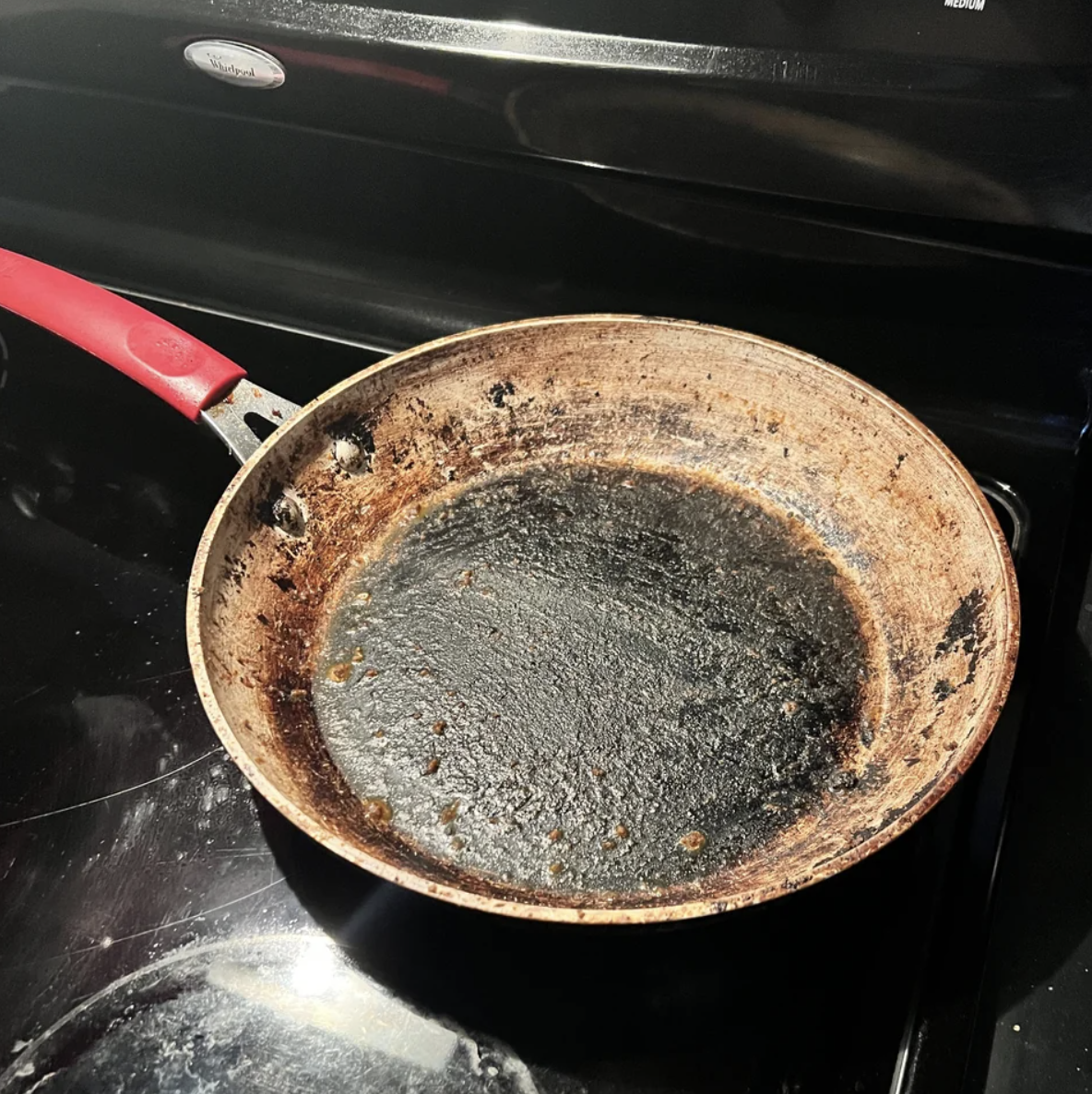 The pan on the stove is very dirty, covered with layers of grime