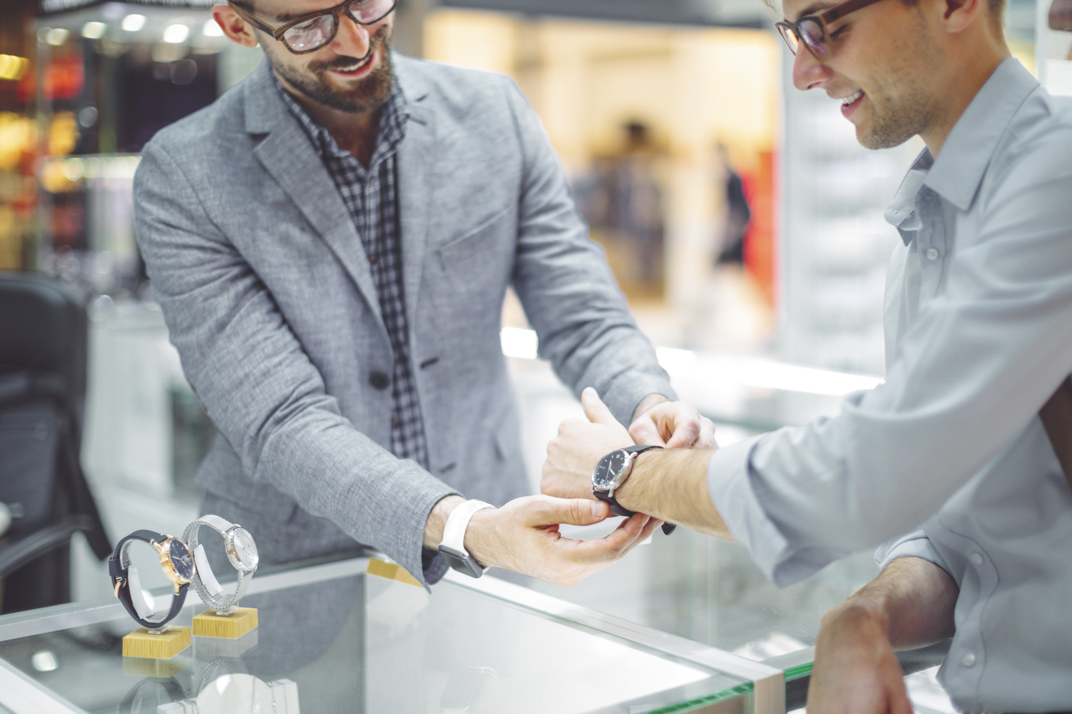 A sales associate putting a watch on a customer