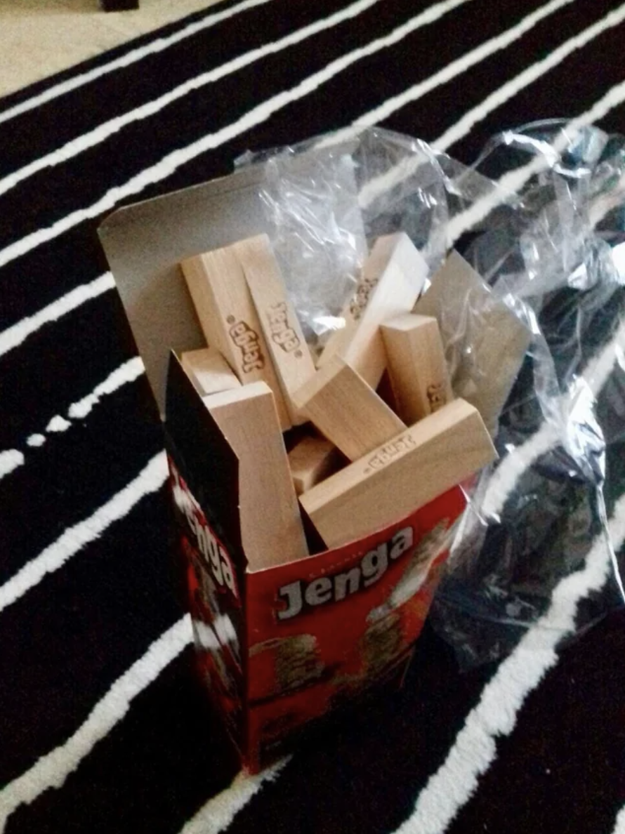 The Jenga pieces are put in the box randomly, so they don&#x27;t fit together and are spilling out of the box
