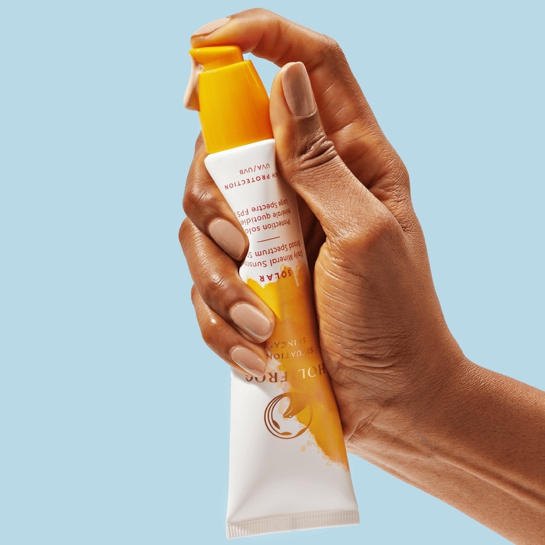 Model holding the Holifrog sunscreen and squeezing some of the sunscreen out of the tube