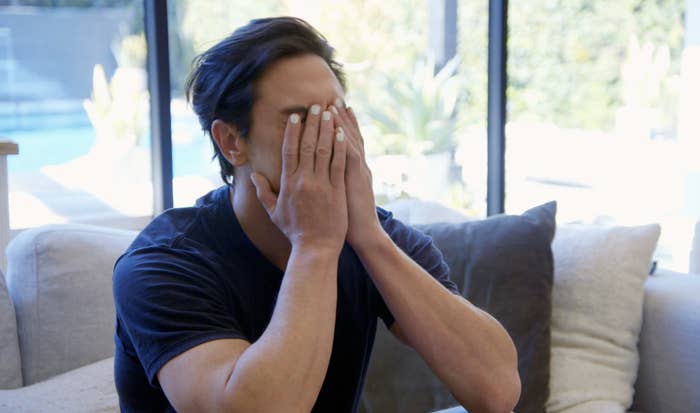 tom covering his face, his nails painted white