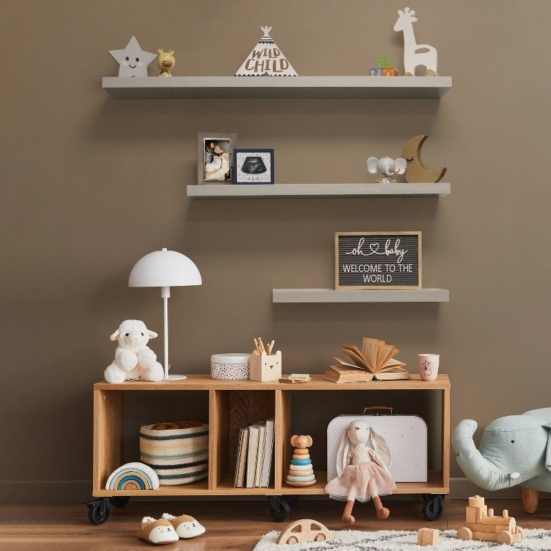 three decorated shelves over a cabinet filled with toys