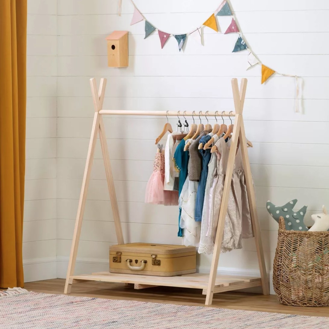 a wooden teepee-like clothing rack with children&#x27;s clothes on it