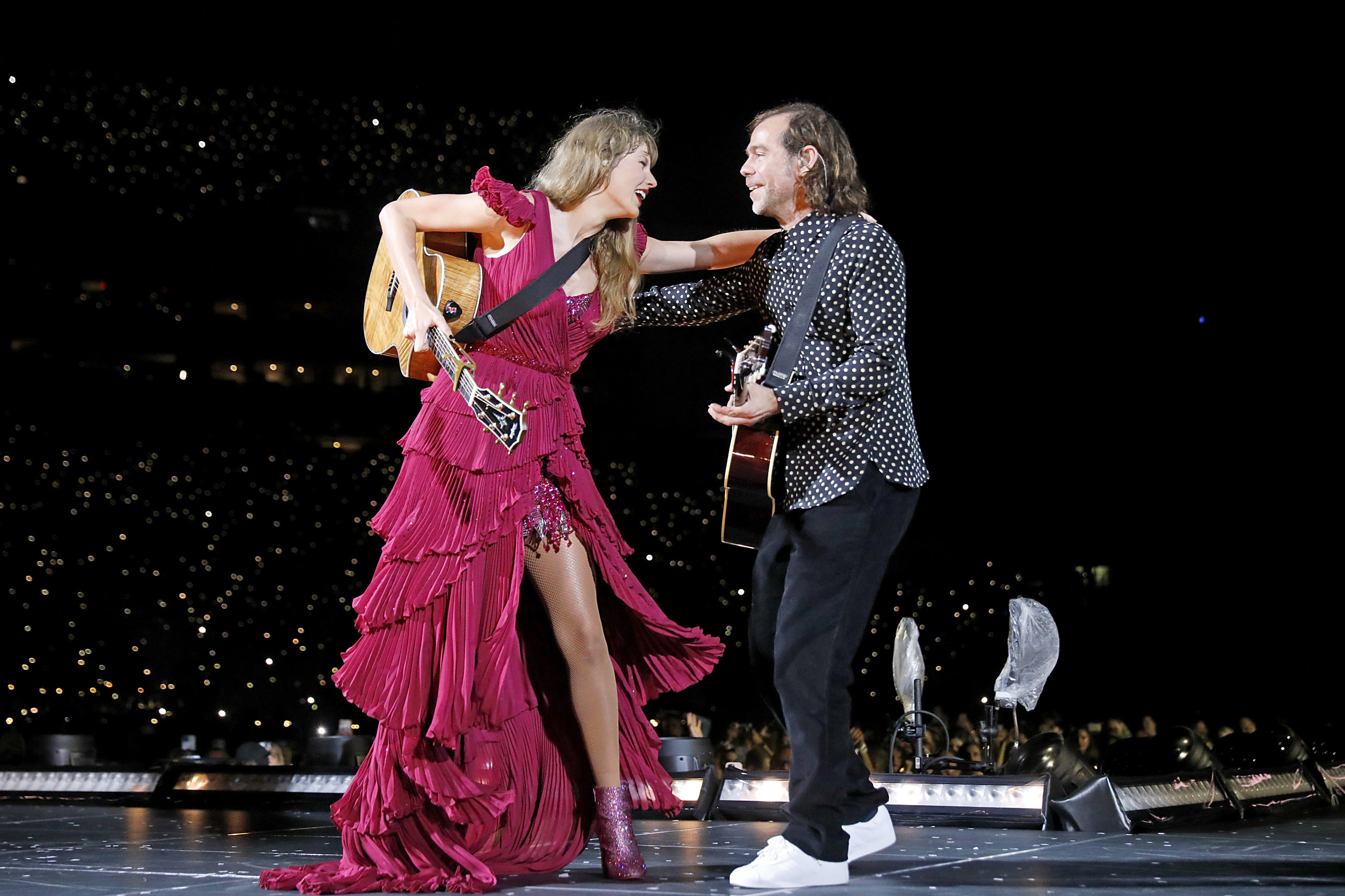 Taylor Swift in a red dress performing with Aaron Dessner