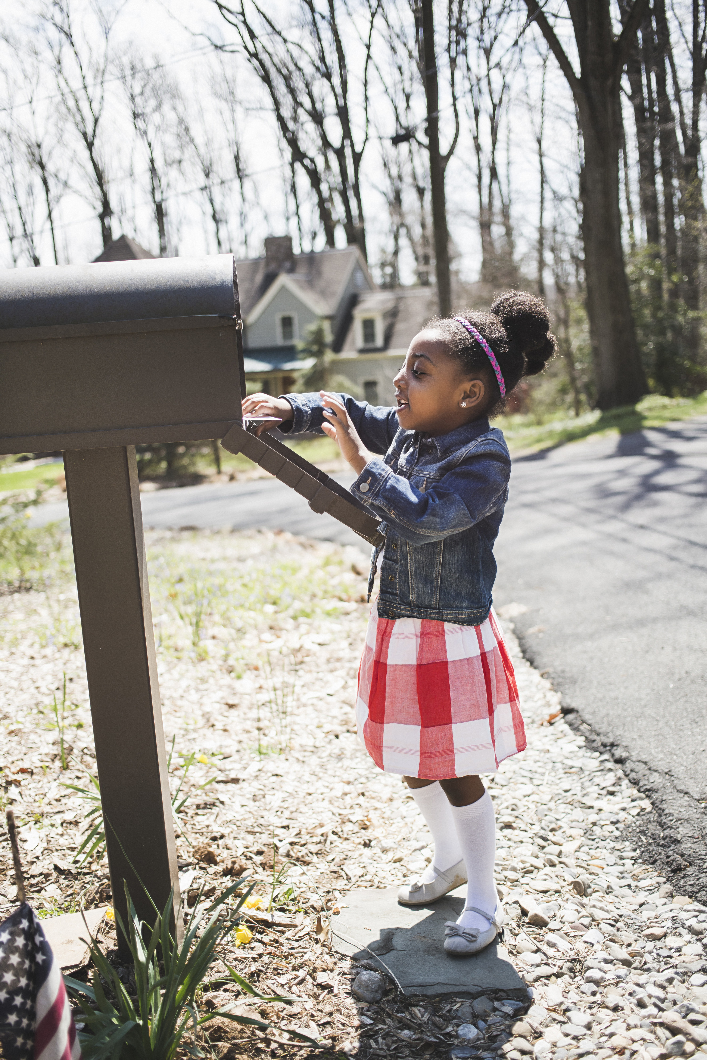 A young girl looks inside her family&#x27;s mail box