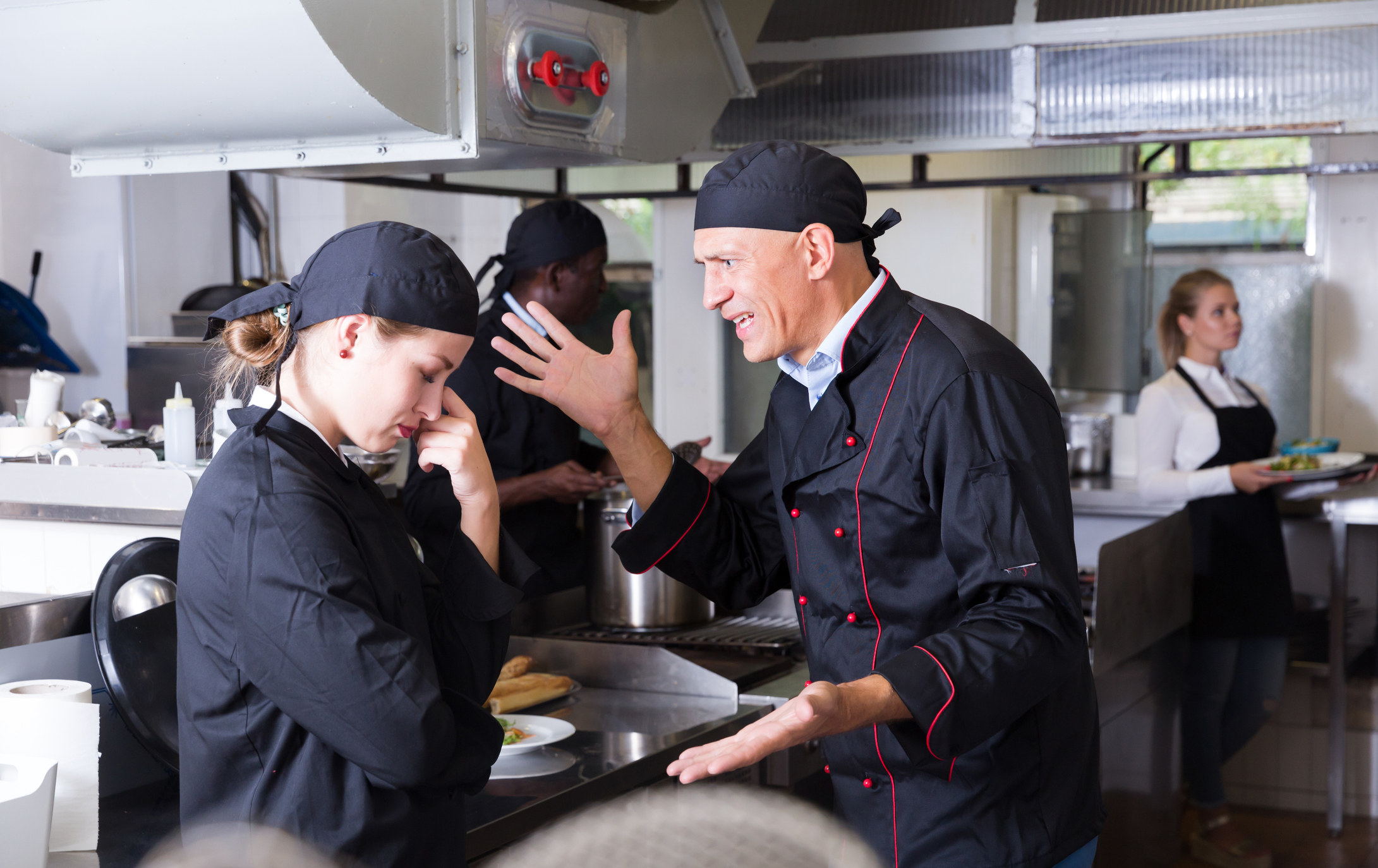 Head chef yelling at another chef in restaurant kitchen