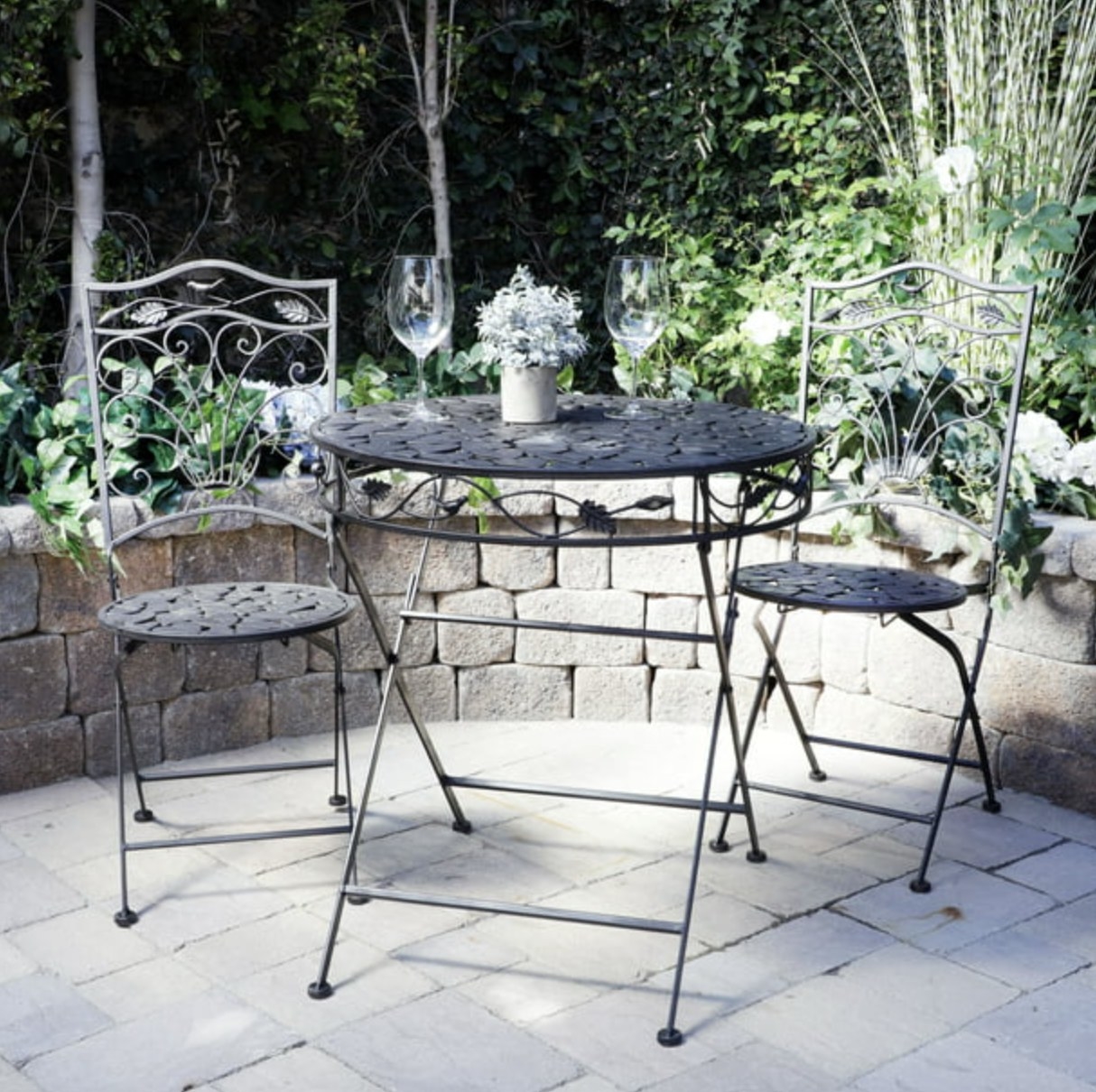the black metal folding chairs and table in a decorated patio space